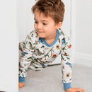 Boy peeking through a doorway wearing the Grow Grows Organic Dandy Dinos Pyjamas | Organic Kids PJs and Nightwear - Clair de Lune UK