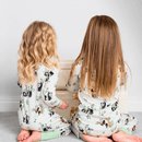 Two girls looking in a toybox wearing matching Grow Grows Organic Playful Pandas Pyjamas | Organic Kids PJs and Nightwear - Clair de Lune UK