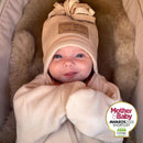 Newborn baby girl rubbing her eyes wearing the oatmeal star fleece baby wrap blanket getting ready for an outdoor adventure with Mother & Baby Shortlist Award 2026 | Cosy Baby Blankets | Swaddle Blanket | Nursery Bedding - Clair de Lune UK