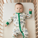 A baby wearing a Safari Slumber Sleepsuit with a gentle safari print, lying comfortably in a crib.