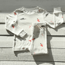 GrowGrows Organic Christmas Eve Pyjamas folded on a grey wooden floor | Organic Kids PJs and Nightwear - Clair de Lune UK