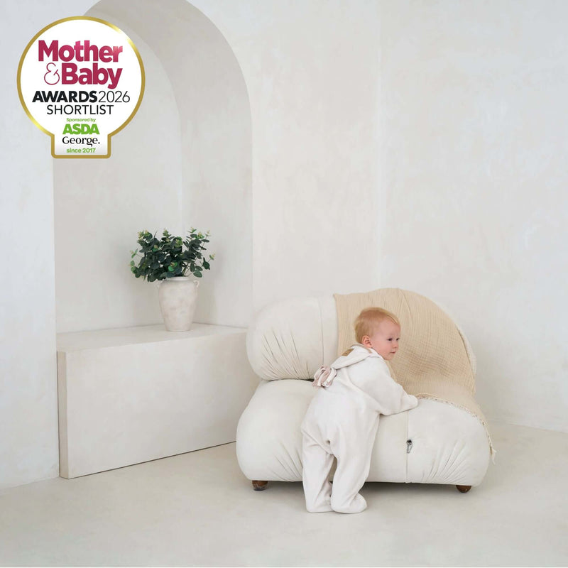 Toddler wearing Cream Star Fleece Baby Wrap Blanket for a winter walk standing by a Cream Chair | Mother & Baby Shortlist Award 2026 | Cosy Baby Blankets | Swaddle Blanket | Nursery Bedding - Clair de Lune UK