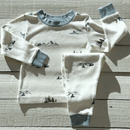 Grow Grows Organic Little Summit Pyjamas folded on a wooden floor | Organic Kids PJs and Nightwear - Clair de Lune UK