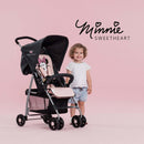 Toddler standing next to her pink Minnie Sweetheart Hauck Disney Sport Pushchair | Prams, Pushchairs & Travel Systems | Baby Travel Essentials - Clair de Lune UK