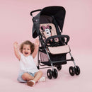Toddler sitting next to her pink Minnie Sweetheart Hauck Disney Sport Pushchair | Prams, Pushchairs & Travel Systems | Baby Travel Essentials - Clair de Lune UK