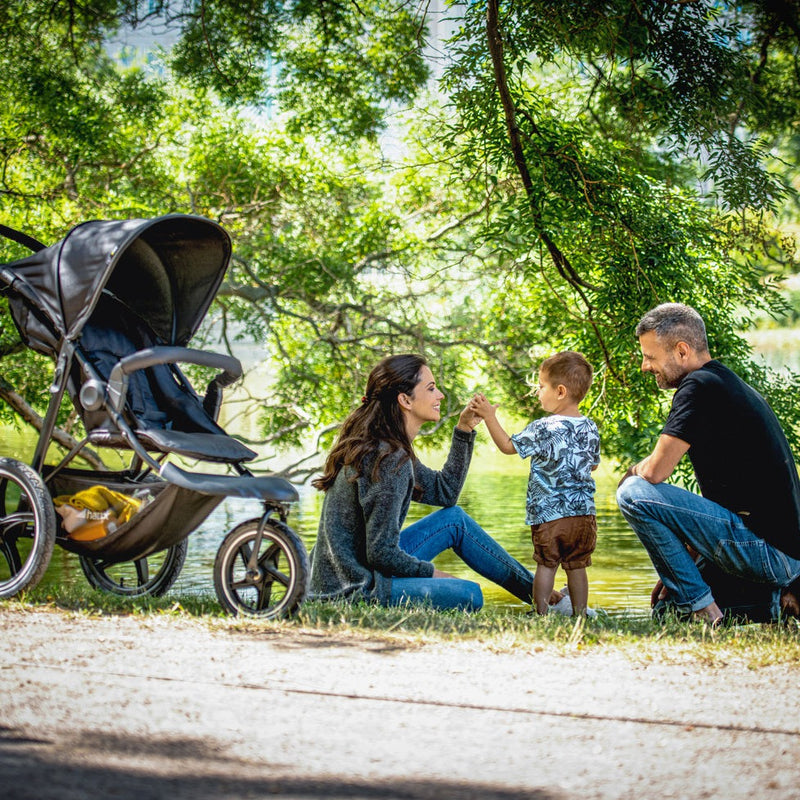 Family enjoying their outdoor time next to the Black Hauck Runner 2 Pushchair | Strollers | Pushchairs, Carrycots & Car Seats Baby | Travel Essentials - Clair de Lune UK