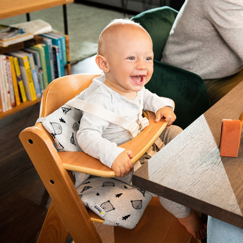Happy toddler sitting on the Hauck Alpha+ Wooden Highchair with Removable Front Bar in Natural | Highchairs | Feeding & Weaning - Clair de Lune UK