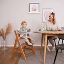 Toddler sitting in the Natural Hauck Alpha+ Wooden Highchair at the table with tray table accessory | Baby Highchairs, stools and seats - Clair de Lune UK