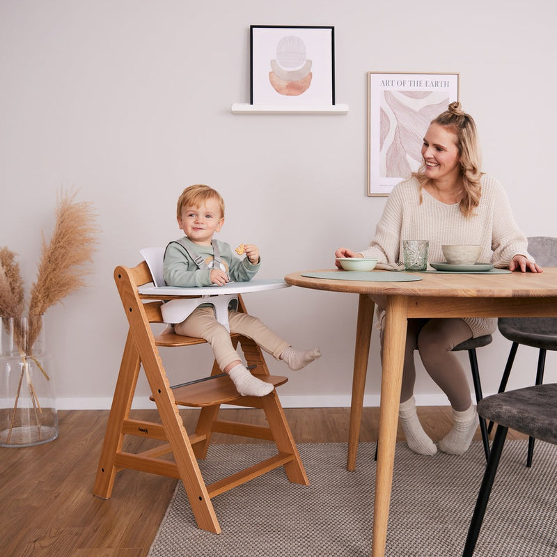 Toddler sitting on the Hauck Alpha+ Wooden Highchair with Removable Front Bar in Natural having dinner with his mom | Highchairs | Feeding & Weaning - Clair de Lune UK