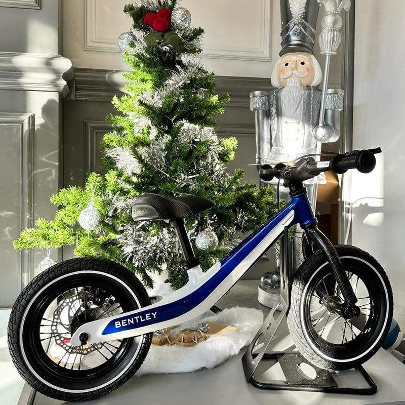 Sequin Blue Glacier White Bentley Balance Bike next to the Christmas tree | Toddler Bikes | Montessori Activities For Babies & Kids - Clair de Lune UK