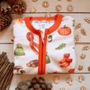 The GrowGrows Autumnal Amazes Sleepsuitfolded on a wooden floor surrounded by acorns, pinecones and pumpkins | Baby Grows and Onesies | Organic Baby Clothes - Clair de Lune UK