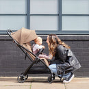 Mum playing with her baby sitting in the Ickle Bubba Aries Max Auto-fold Stroller in Biscuit | Prams, Pushchairs & Travel Systems | Baby Travel Essentials - Clair de Lune UK