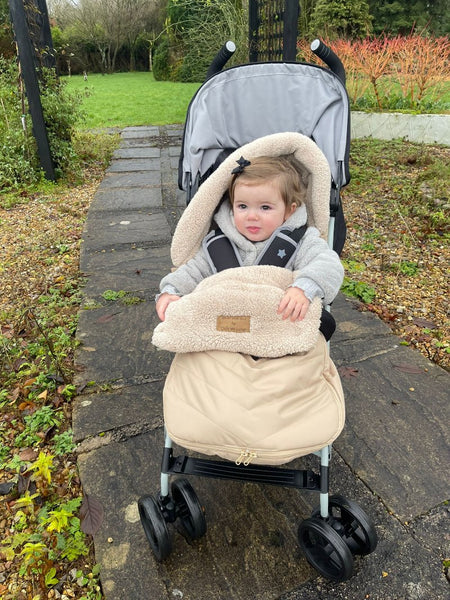 Baby girl in the pram wrapped up in a beige snug footmuff | Pushchair Accessories | Baby Winter Warmers - Clair de Lune UK