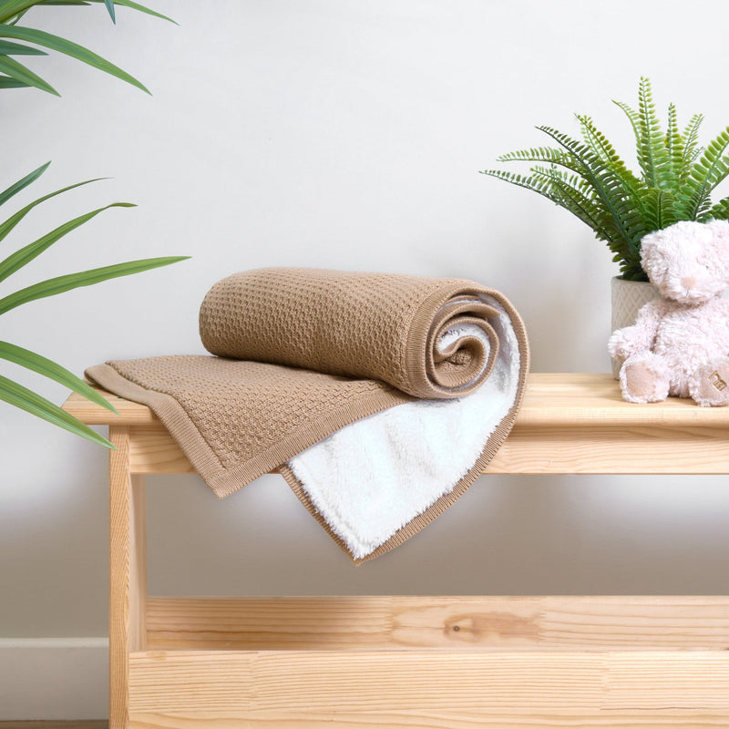 Rolled Organic Knit Sherpa Baby Blanket in Biscuit Brown on a changing unit next to a teddy bear and plant | Cosy Baby Blankets | Swaddles | Baby Winter Warmers - Clair de Lune UK