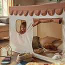 Girl peeking through the window of the CuddleCo Play House With Bunting - Tuscany in a cosy living room | Children's Imaginative Play | Toddler Toys and Gifts - Clair de Lune UK