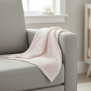 Pink Soft Cotton Cellular Shawl draped over the side of a grey feeding chair in the nursery | Baby Blankets | Nursery Bedding - Clair de Lune UK