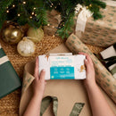 Jungle Dream Moses Basket Sheets being unwrapped under the Christmas tree surrounded by xmas decorations and stunning gifts | Soft Baby Sheets | Baby Nursery Bedding | Baby's First Christmas Gifts - Clair de Lune UK