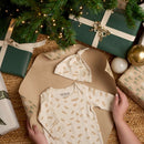 Little Dreamers Luxury Organic Gift Set being unwrapped by the Christmas tree surrounded by green and cream gifts shows the hat and the body suit| Baby's First Christmas | Organic Baby Gift - Clair de Lune UK