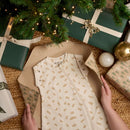 Little Dreamers Luxury Organic Swaddle Bag being unwrapped on Christmas morning surrounded by gorgeous green gifts | Baby Sleeping Bags | Organic Nursery Bedding | Baby's First Christmas Gifts - Clair de Lune UK