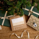 Organic Knit Sherpa Travel Blanket in cream in eco brown box packaging sitting under the Christmas tree surrounded by beautifully wrapped gifts | Cosy Baby Blankets | Swaddles | Baby Winter Warmers - Clair de Lune UK