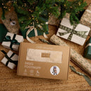 Beige Snug Universal Pushchair Footmuff in a gift box sitting under the tree on Christmas morning surrounded by presents in green and cream | Pushchair Cosytoes & Footmuffs | Travel Accessories | Baby Christmas Gifts - Clair de Lune UK