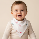 A smiling baby wearing a cream-colored long-sleeve top and a GrowGrows Christmas Eve Baby Bib with a festive Christmas print of stockings, Santa hats, and reindeer. | Feeding Essentials - Clair de Lune UK