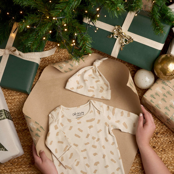 Little Dreamers Organic Onesie and hat being wrapped up under the chistmas tree | Newborn Baby Gifts | Baby's First Christmas Gift - Clair de Lune UK