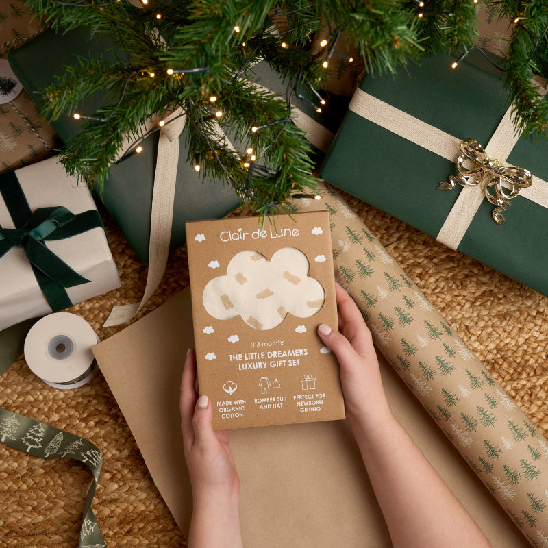 Mum opening the Little Dreamers Organic Luxury Gift Set by the Christmas tree with luxury green and cream gifts | Baby's First Christmas | Baby and Toddler Christmas gifts 2025 - Clair de Lune UK