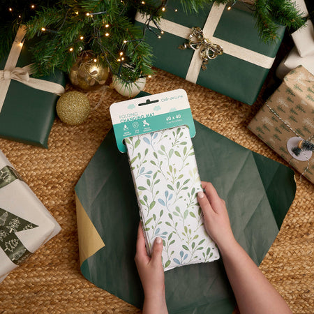 Mum opening the Olive Foldable Travel Changing Mat surrounded by Christmas gifts | Baby Gift Ideas | Christmas Gifts for Baby and Toddler - Clair de Lune UK
