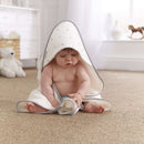 Gorgeous baby boy sat on the floor of the nursery wearing the Lullaby Hearts Cream and White Hooded Baby Towel | Baby Bathtime Accessories | Baby Shower Gifts - Clair de Lune UK