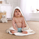 Gorgeous baby boy sat on the floor of the nursery wearing the Lullaby Hearts Cream and White Hooded Baby Towel | Baby Bathtime Accessories | Baby Shower Gifts - Clair de Lune UK