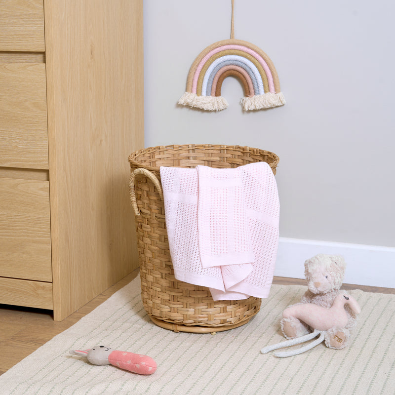 Pink Soft Cotton Cellular Blanket draped in a wicker basket next to a changing unit | Cosy Baby Blankets | Nursery Bedding | Newborn, Baby and Toddler Essentials - Clair de Lune UK