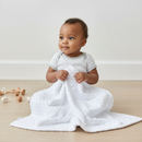 Baby smiling in the nursery holding the White Marshmallow Blanket | Baby Blankets & Swaddles - Clair de Lune UK