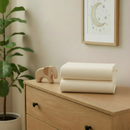 Cream 2 Pack Universal Fitted Cotton Moses Basket Sheets - 74 x 30 cm folded on a changing unit in the nursery | Soft Baby Sheets | Moses Basket Bedding - Clair de Lune UK