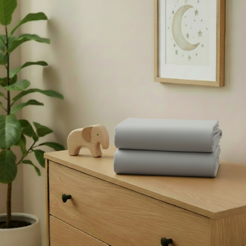 Grey 2 Pack Universal Fitted Cotton Moses Basket Sheets - 74 x 30 cm folded on a changing unit in the nursery | Soft Baby Sheets | Moses Basket Bedding - Clair de Lune UK