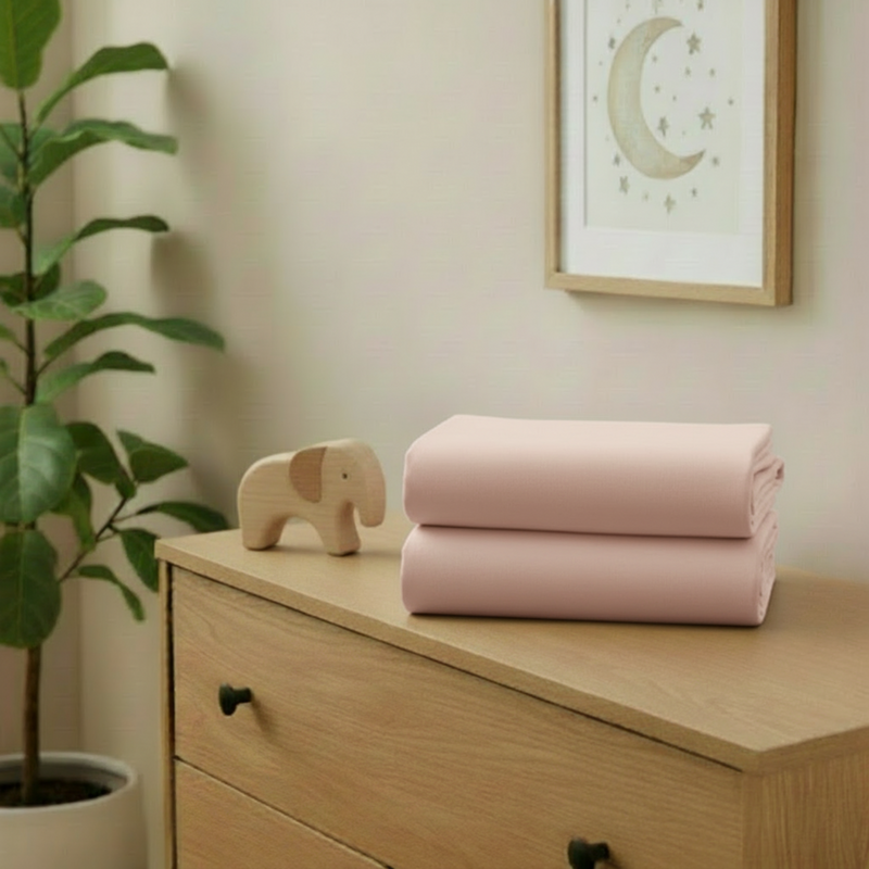 Pink 2 Pack Universal Fitted Cotton Moses Basket Sheets - 74 x 30 cm folded on a changing unit in the nursery | Soft Baby Sheets | Moses Basket Bedding - Clair de Lune UK