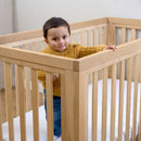 Baby playing inside the Oak Cot Bed in a Scandi Natural Nursery Room | Cots, Cot Beds, Toddler & Kid Beds | Baby Bed | Nursery Furniture - Clair de Lune UK