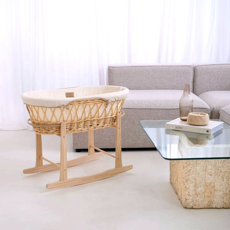 Cream Organic Natural Wicker Moses Basket on the Natural Rocking Stand in a minimalist, ultra-stylish living room next to a grey corner sofa and cork and glass coffee table | Moses Baskets | Co-sleepers | Nursery Furniture - Clair de Lune UK