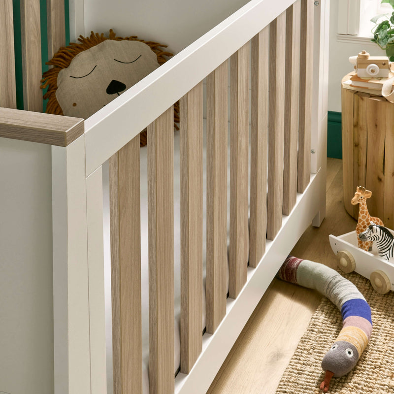 The natural wood details of the White and Natural Cot Bed from the CuddleCo Ada Cot Bed & Nursery Room Sets in a trendy green nursery room | Nursery Furniture Sets | Room Sets | Nursery Furniture - Clair de Lune UK