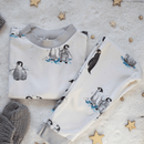 GrowGrows Organic Plodding Penguins Pyjamas folded on a sparkling snow background | Organic Kids PJs and Nightwear - Clair de Lune UK
