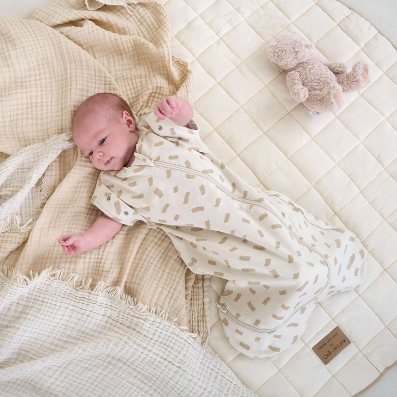 Newborn baby wearing the Little Dreamers Luxury Organic Swaddle Bag on the Organic Play Mat | Baby Swaddle Bag | Newborn Sleeping Bag | Nursery Bedding - Clair de Lune