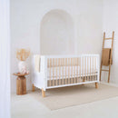 White Essentials Cot Bed Clearance in a super stylish white minimalist nursery room by a wooden night stand and ladder for the organic knit blanket | Cots, Cot Beds & Toddler Beds | Nursery Furniture - Clair de Lune UK