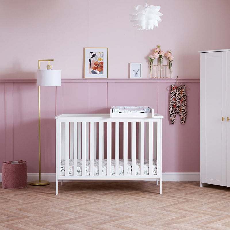 White Obaby Evie Mini Cot Bed in a pastel pink Disney princess-theme nursery room with the cot top changer | Cots, Cot Beds, Toddler & Kid Beds | Nursery Furniture - Clair de Lune UK