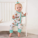 Toddler girl sat on the edge of her cot wearing the GrowGrows Organic Tropical Turtles Sleepsuit | Baby Grows and Onesies | Organic Baby Clothes - Clair de Lune UK