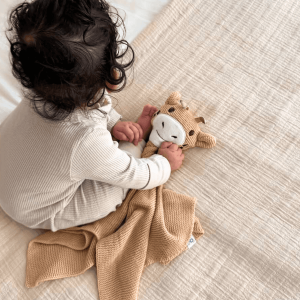 Baby holding the GrowGrows Giraffe Animal Comforter- Clair de Lune UK