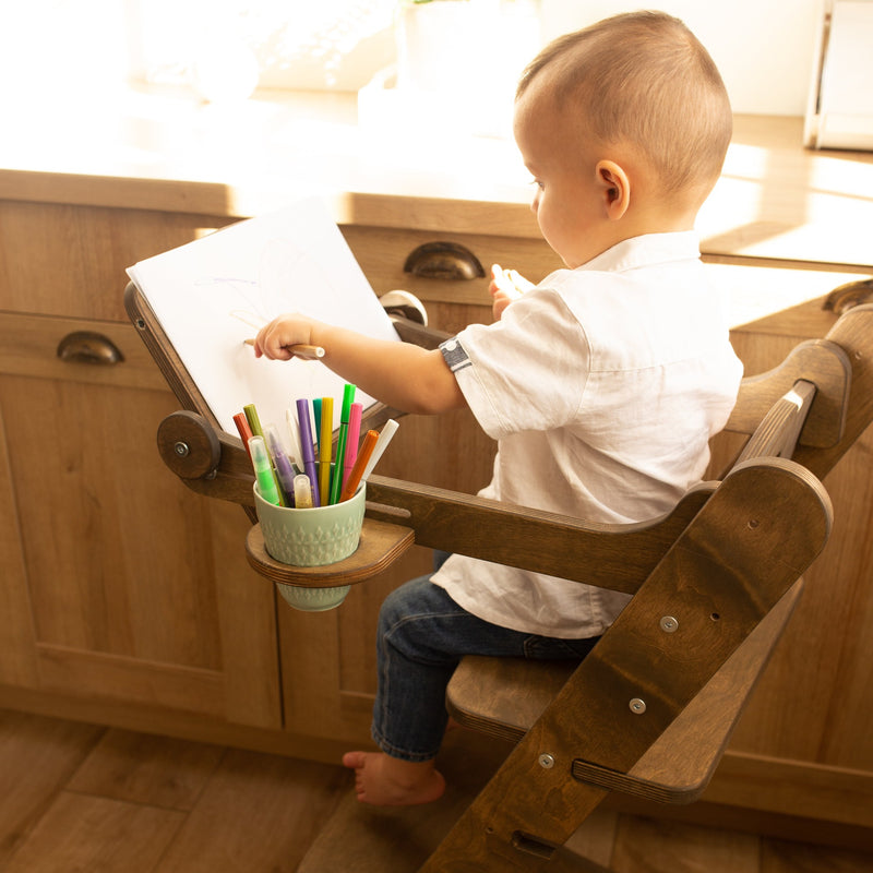  A boy reading a book while sitting on the Chocolate Goodevas 3in1 Highchair with Adjustable Tabletop | Highchairs | Feeding & Weaning - Clair de Lune UK