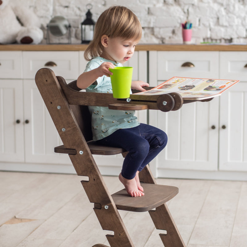A girl reading books while sitting on the Chocolate Goodevas 3in1 Highchair with Adjustable Tabletop | Highchairs | Feeding & Weaning - Clair de Lune UK