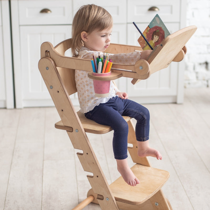 A girl reading books while sitting on the Natural Goodevas 3in1 Highchair with Adjustable Tabletop | Highchairs | Feeding & Weaning - Clair de Lune UK