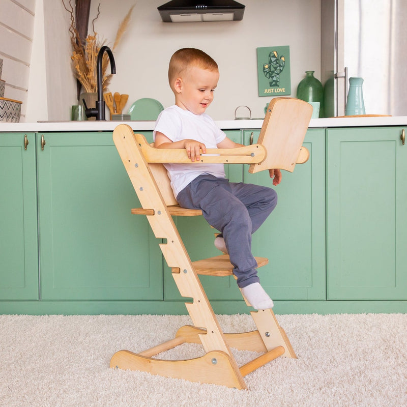 A boy studying while sitting on the Natural Goodevas 3in1 Highchair with Adjustable Tabletop in the kitchen | Highchairs | Feeding & Weaning - Clair de Lune UK
