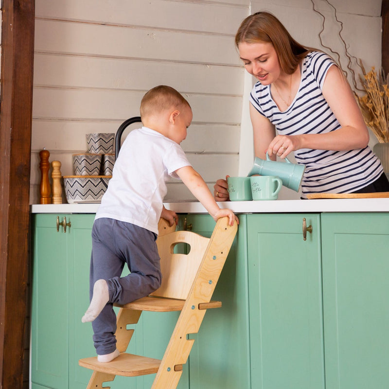 A boy helping his mom in the kitchen by climbing on the Natural Goodevas 3in1 Highchair with Adjustable Tabletop | Highchairs | Feeding & Weaning - Clair de Lune UK